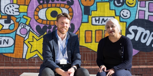 A member of staff with Headteacher of local school sat on a bench